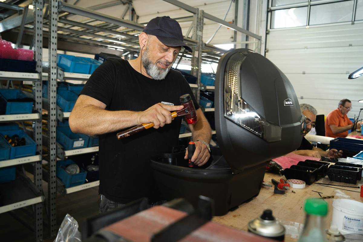 Close-up of a technician using a wrench to fix gaming chair recliner mechanism beneath seat base